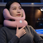 A woman wearing a gray knit sweater rests in a luxurious vehicle or lounge chair, using a light pink neck pillow with a built-in massage or heating function.