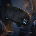 A dark gray sleep mask with a built-in control panel and blue LED lights, floating against a dark background with flowing blue ribbons and warm bokeh light effects.