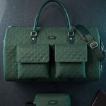 A dark green textured duffel bag with two front flap pockets, top handles, and a shoulder strap, shown on a dark background with a matching small pouch below and a brown wallet at the lower right.