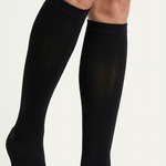 A pair of black knee-high compression socks worn on a person's legs, shown against a plain light background.