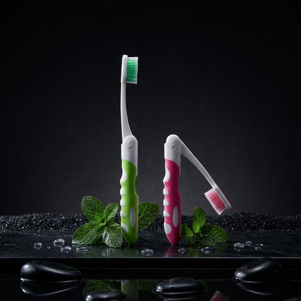 Two folding travel toothbrushes standing upright on a dark surface