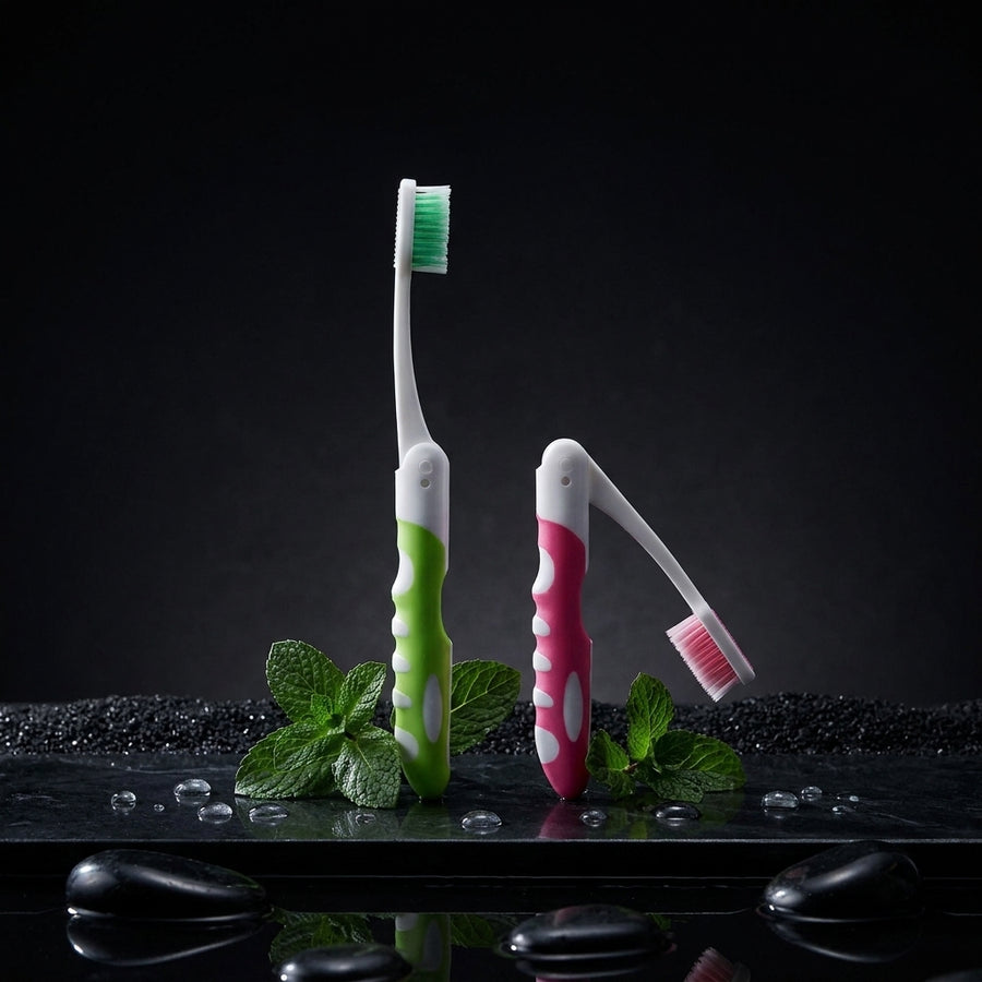 Two folding travel toothbrushes standing upright on a dark surface
