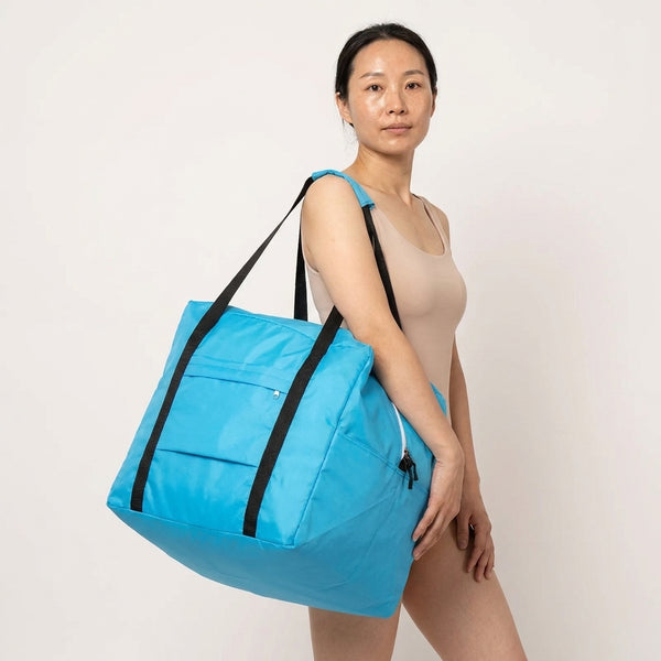 A woman carrying a booster seat travel bag in bright blue