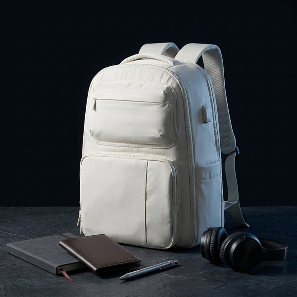 The personal-item backpack in beige with a notebook, pen and headphones