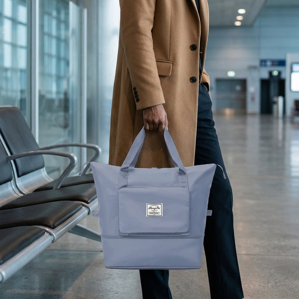 A traveller carrying a foldable travel duffel in an airport hall
