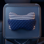A car center console armrest tray holding a padded neck pillow with a navy blue quilted section and a navy-and-white striped top section, shown inside a vehicle interior.
