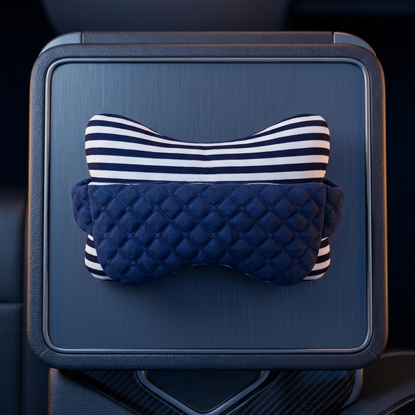 A car center console armrest tray holding a padded neck pillow with a navy blue quilted section and a navy-and-white striped top section, shown inside a vehicle interior.