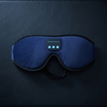 A dark blue sleep mask with a built-in digital control panel, resting on a dark textured surface.