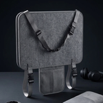 A gray travel neck pillow set displayed on a dark surface against a black background, including a rectangular travel pillow with adjustable straps, a folded gray blanket, a black sleep mask, and a pair of black over-ear headphones.