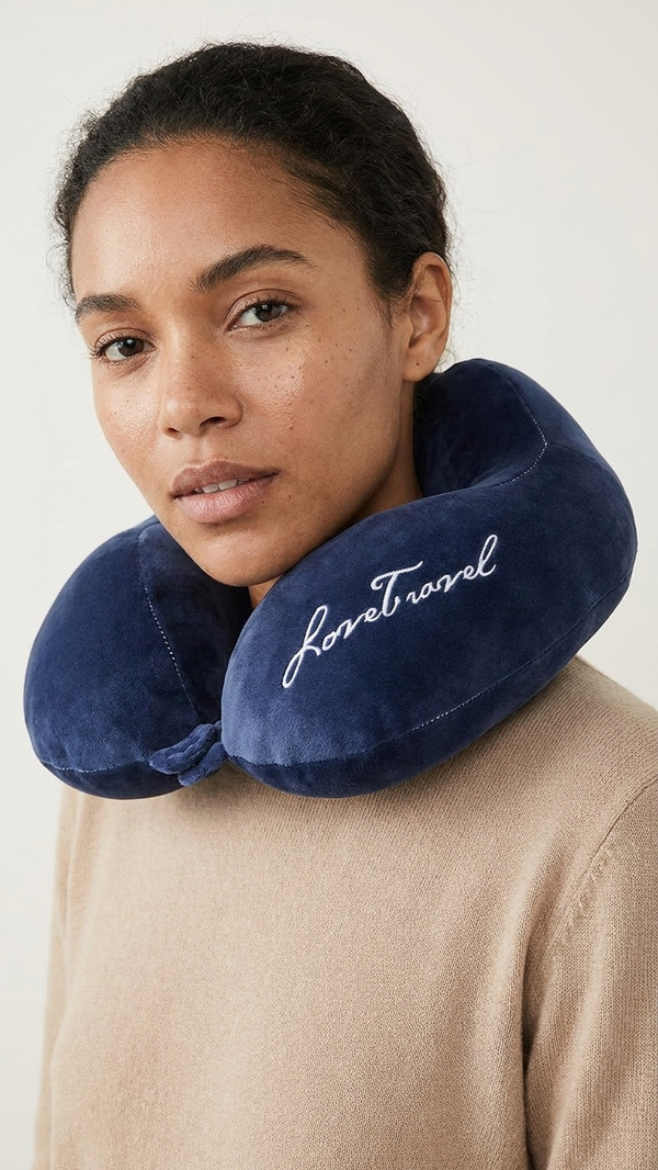 A woman wearing a U-shaped travel pillow in navy velvet